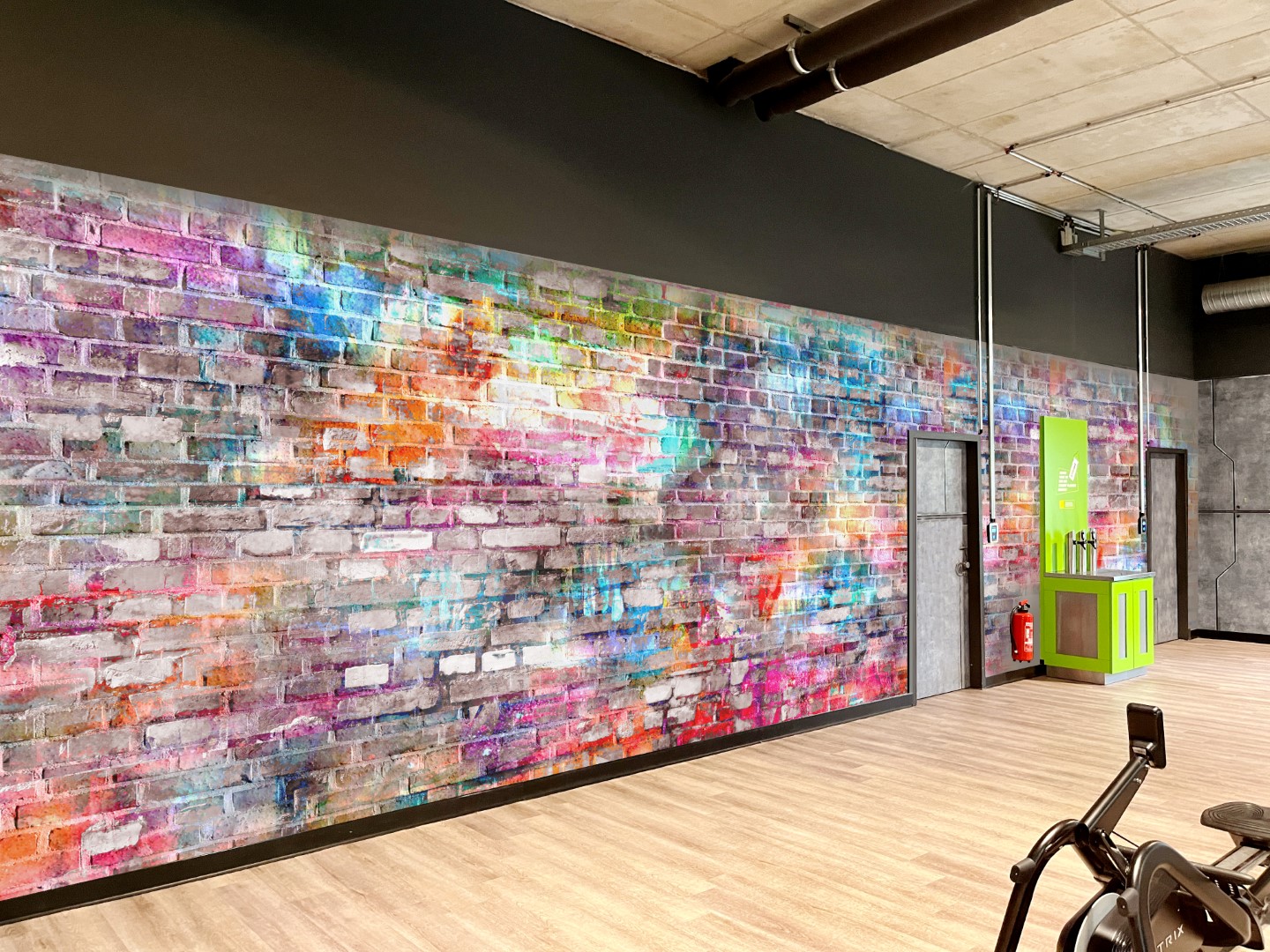 Fototapete mit bunter Backsteinwand im Graffiti-Stil als moderner Wandbelag in einem Fitnessstudio